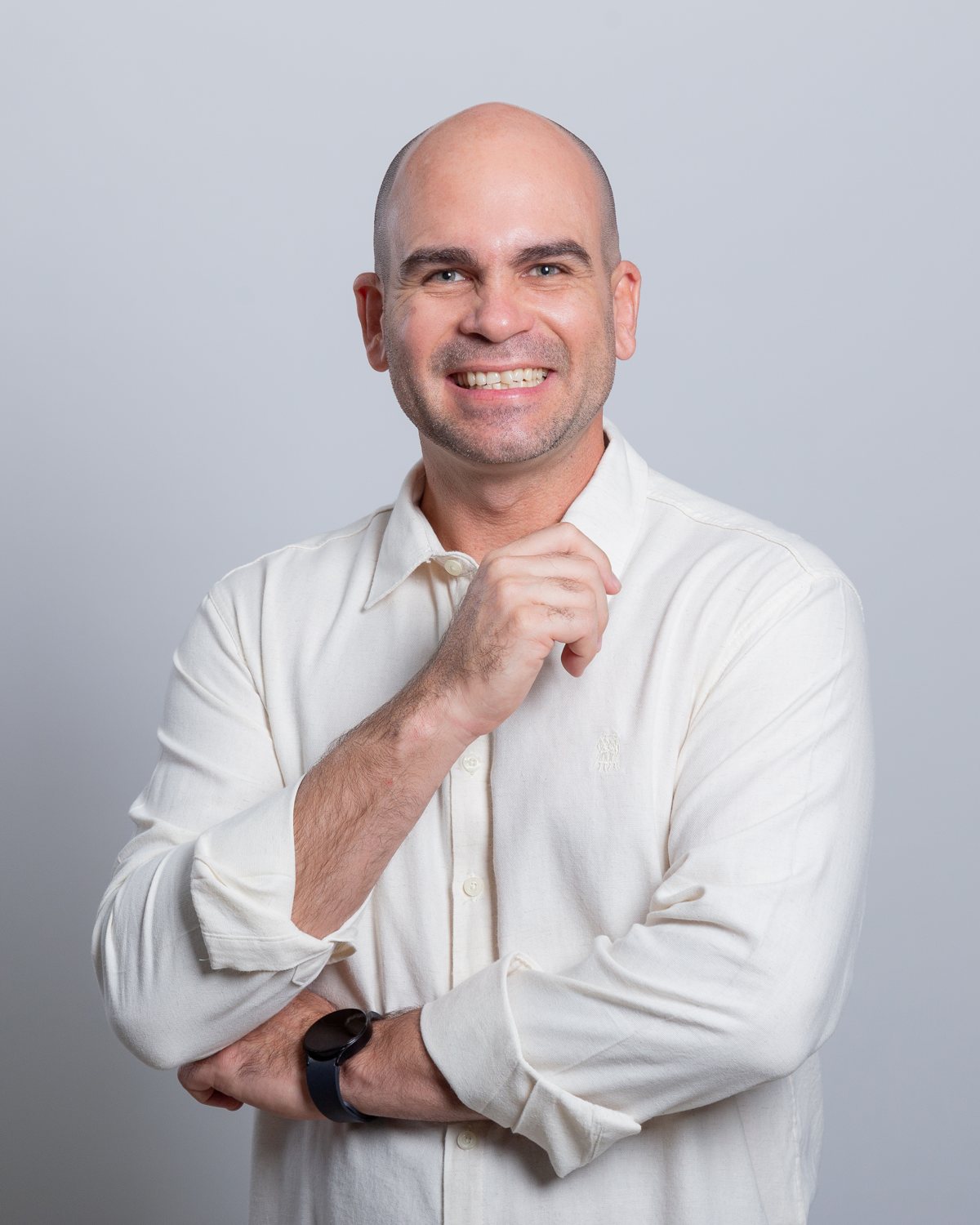 Felipe Lapa, de camisa de botão clara, sorrindo, em retrato de estúdio