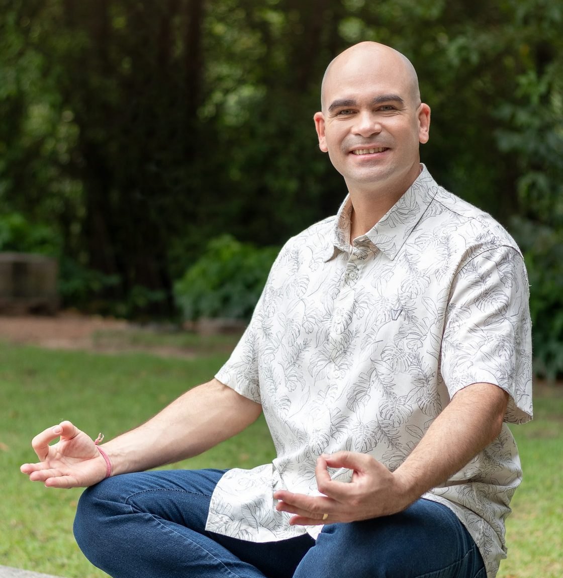 Felipe Lapa sentado em meditação, ao ar livre, sorrindo