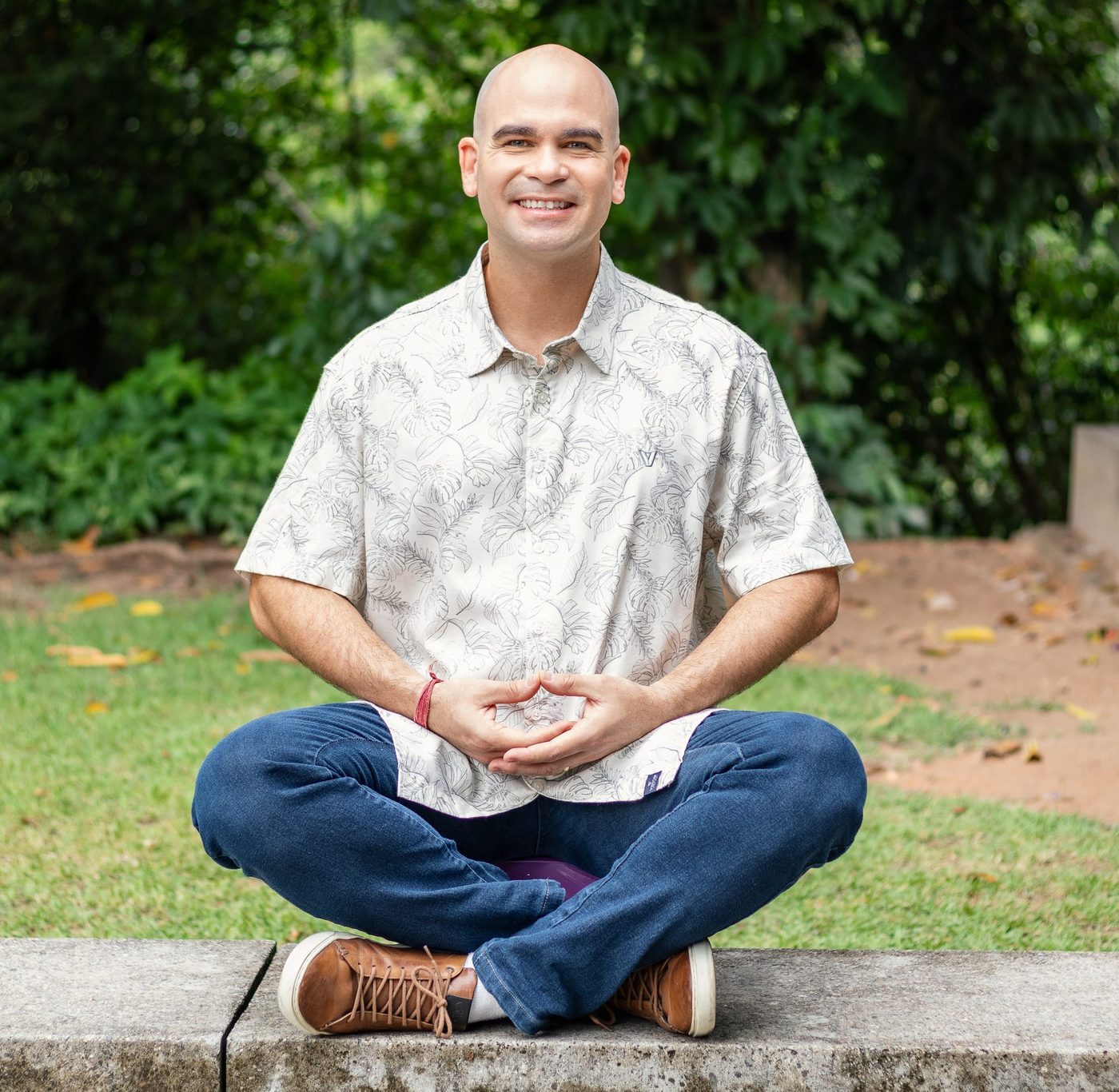 Felipe Lapa sentado na grama, em meditação, sorrindo